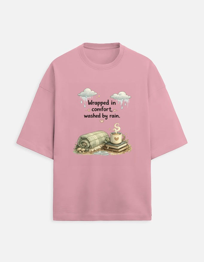Snuggle Spot oversized pink terry-knit t-shirt with a graphic print of a cozy blanket, coffee, and rainy clouds.