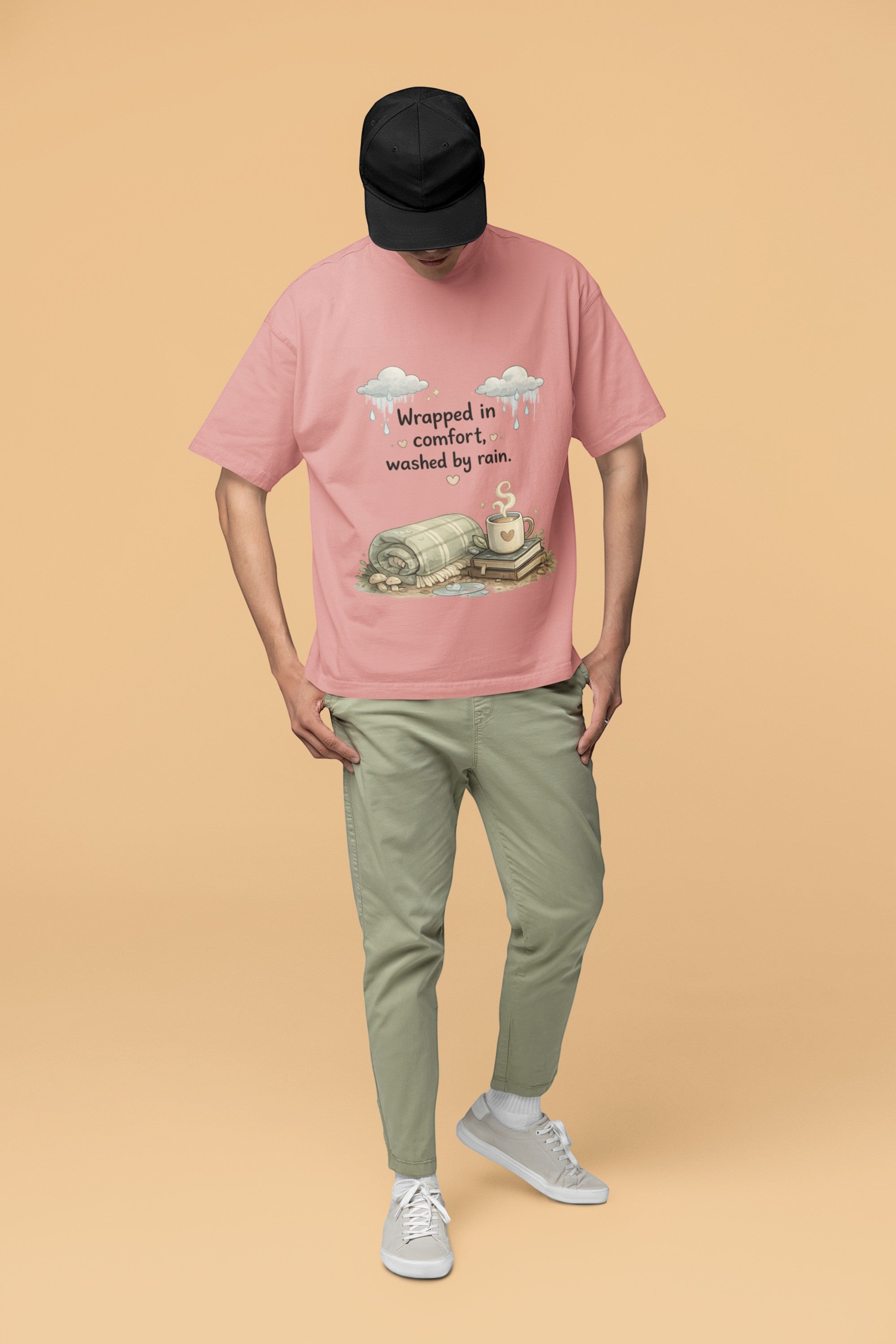 Snuggle Spot unisex oversized pink terry-knit t-shirt with graphic print, worn by a man in a black cap and olive pants.